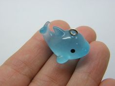 a small blue plastic animal with a ring on it's thumb in someones hand