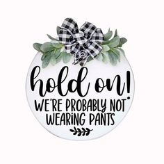 a white ornament with a black and white bow on it that says hold on, we're probably not wearing pants