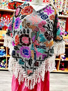 These beautiful Mexican ponchos (aka mañanitas) are handmade in Hueyapan Puebla. Every poncho bears unique hand-embroidery according to the traditions of the community. Measuring approximately 34" wide by 26'' long, one size should fit all adults. All ponchos can be worn 2 ways: Flat across the front or point down, for a longer, more flowing look. (Each piece may slightly vary from the model in the photo) Black Peacock, Mexican Gifts, Mexican Outfit, Mexican Jewelry, Tropical Decor, The Community, Hand Embroidered, Hand Embroidery, Gift Shop