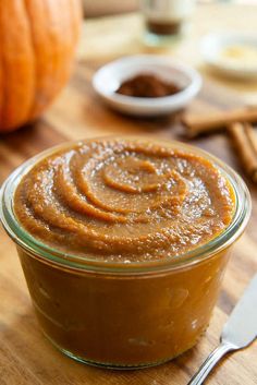 a glass jar filled with peanut butter sitting on top of a wooden table next to spoons