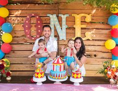 a family posing for a photo in front of a carnival theme backdrop at their birthday party