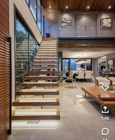 a living room filled with lots of furniture next to a stair leading up to a large window