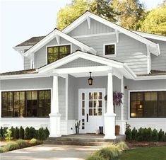 a white house with gray trim and black shutters on the front door is shown