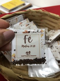 a person holding up a packet of seeds in front of a basket full of packets