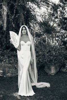 a woman in a wedding dress is holding an umbrella and posing for a black and white photo