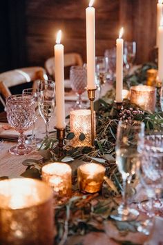 the table is set with candles and greenery