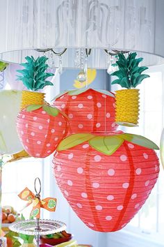 two paper strawberries hanging from a chandelier with pineapples on them