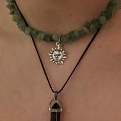 a woman wearing a green necklace with a sun charm