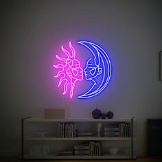 a neon sign in the shape of a sun and moon on a wall next to a bookshelf