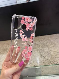 a woman holding up her phone case that has pink flowers on the front and bottom