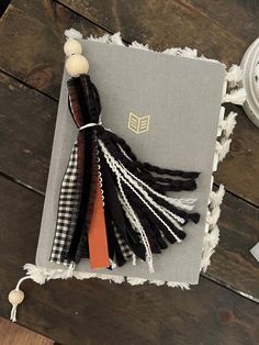 a book with tassels on top of it sitting on a wooden table next to a clock