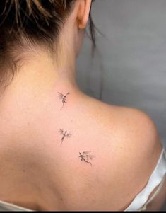 the back of a woman's neck with three small birds on her left shoulder