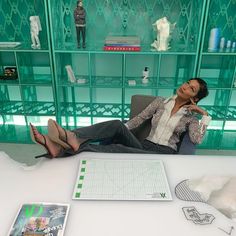 a woman sitting on a chair in front of a table with paper, scissors and figurines