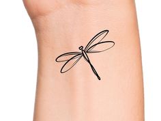 a small black dragonfly tattoo on the right side of a woman's arm