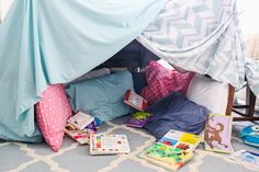 a child's bed with blue covers and books on the floor