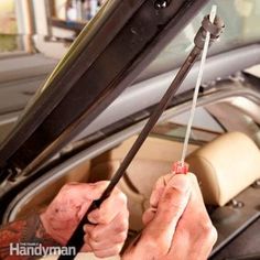 a man is working on the windshield of his car while holding a wrench with both hands