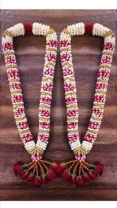 two red and white beads are attached to a wooden wall with flowers on the side