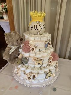 a teddy bear sitting next to a multi layer diaper cake on top of a table