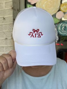 a person wearing a white hat with the word ata on it and two red bows