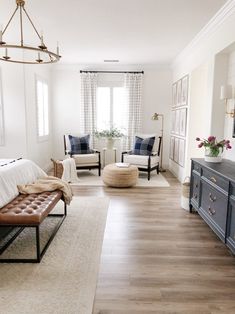 a bedroom with white walls and wood flooring is pictured in this image, there are two chairs on either side of the bed