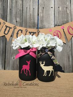 two painted jars with flowers and deer on them are sitting in front of a wooden fence