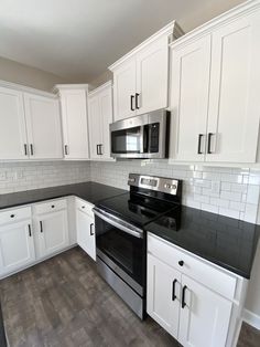 an empty kitchen with white cabinets and black counter tops is pictured in this image from the front view