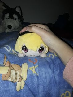 a person is holding a stuffed animal on a bed with other stuffed animals in the background