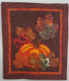 a quilted wall hanging with autumn leaves and pumpkins on it's side