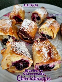 blueberry cheesecake chimichangas are on a plate with powdered sugar