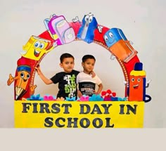 two young boys standing in front of a sign that says, first day in school