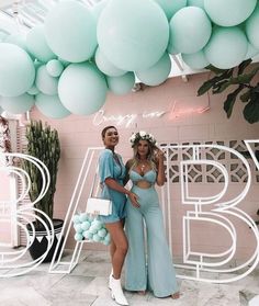 two women standing next to each other in front of balloons