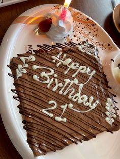 a birthday cake with chocolate frosting and candles on a plate next to other desserts