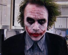 a man dressed up as the joker with his hair pulled back and makeup painted red