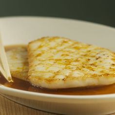 a white bowl filled with food on top of a wooden table next to chopsticks