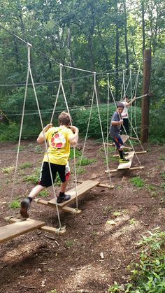 three children are playing in the woods on swings made from wood planks and rope