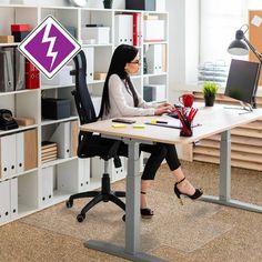 a woman sitting at a desk in front of a book shelf with a purple lightning sign on it