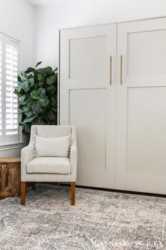 a white chair sitting in front of a wooden table on top of a rug next to a door