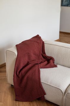 a white couch with a red blanket on it