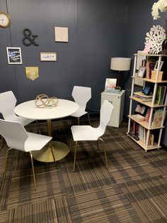 there is a table and four chairs in the room with bookshelves on the wall