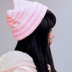 a woman with long black hair wearing a pink and white knitted hat on her head