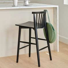 a black chair with a green bag sitting on it's back in front of a counter