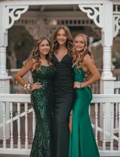 three beautiful women in long dresses posing for the camera with their arms around each other