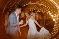 a man and woman are dancing in a room with light streaks on the wall behind them