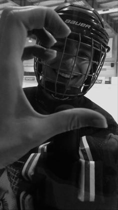 a black and white photo of a person wearing a football helmet with their fingers in the air