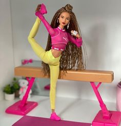 a barbie doll is standing on a bench with her leg up and holding a drink