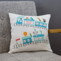 a pillow with a train design on it sitting on a couch next to a chair