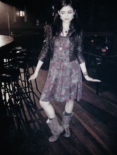 a woman standing on top of a wooden floor next to bar stools and tables