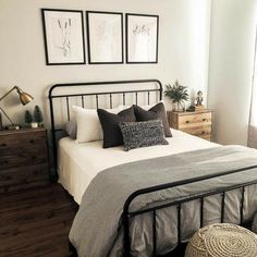 a bedroom with white walls and black metal bedspread, two framed pictures on the wall