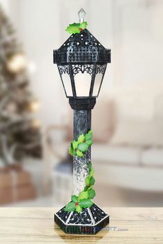 a decorative lamp on a table with a christmas tree in the background