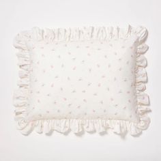 a white pillow with pink flowers and ruffles on the bottom, against a white background